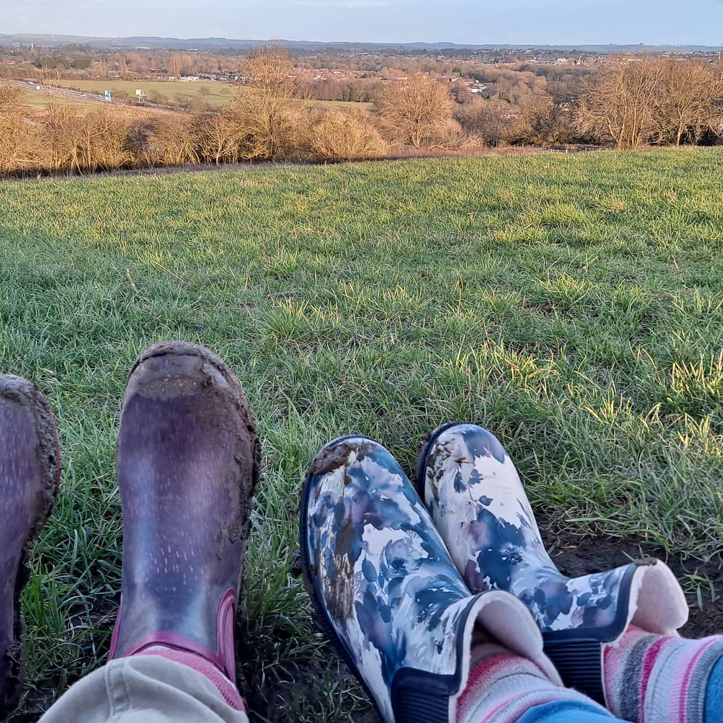 two peoples wellie boots at the top of a hill in the winter sunshine