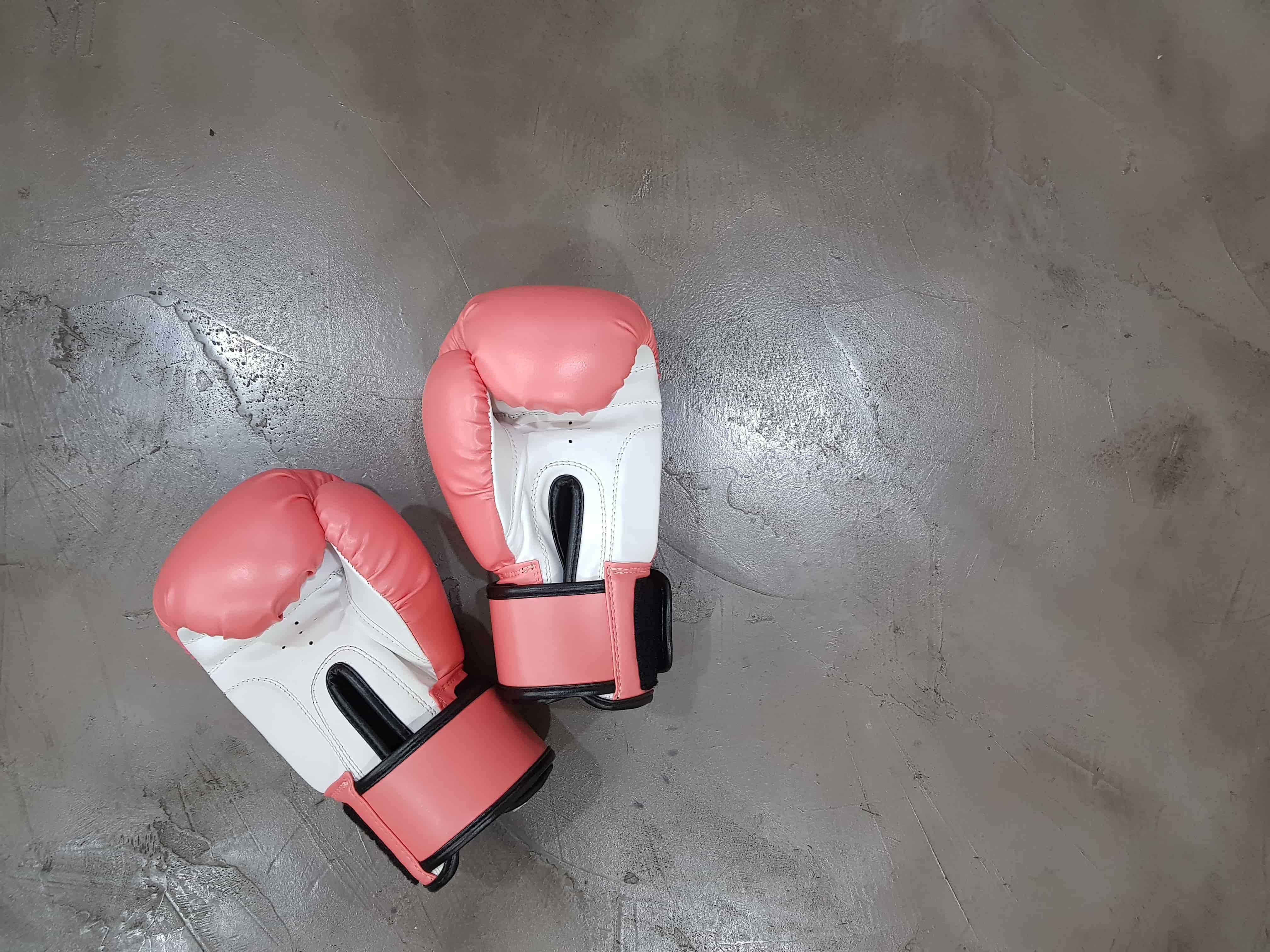 Red and white boxing gloves lying on grey floor 