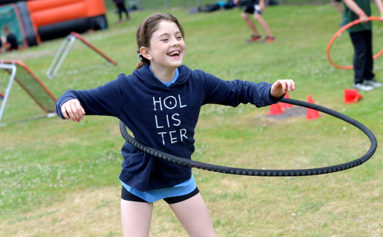 young girl in blue hooded top hula hooping