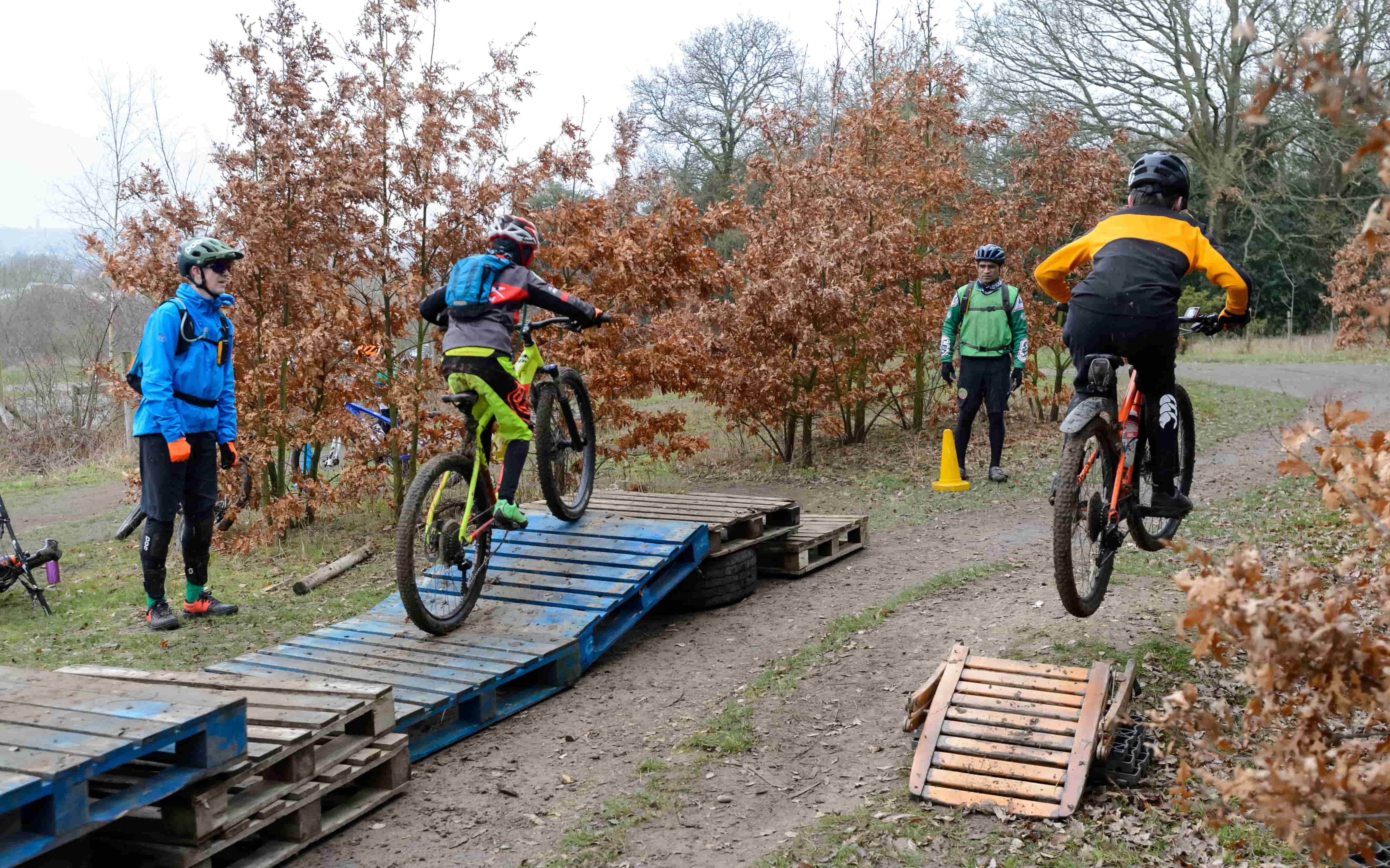 two people on mountain bikes being coaches to go over a ramp
