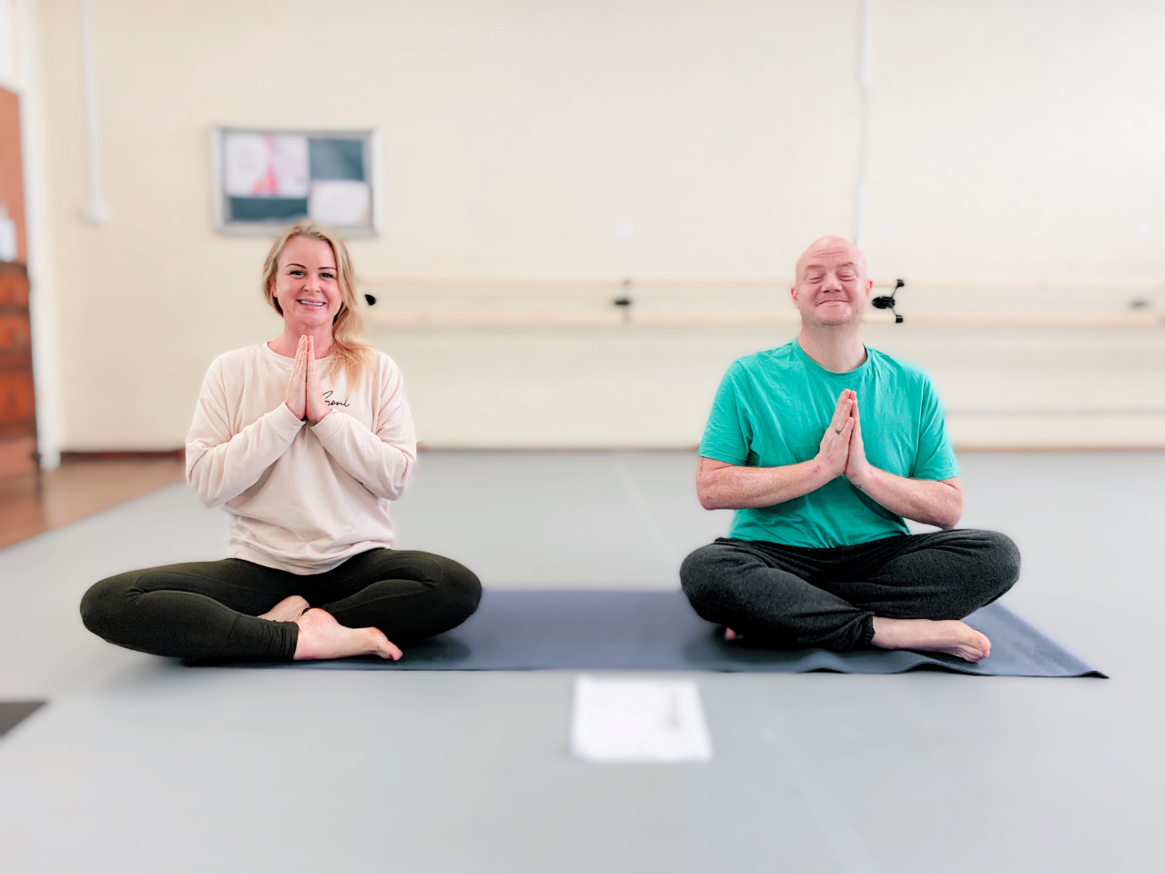 Man and women on a yoga mat in sitting yoga pose