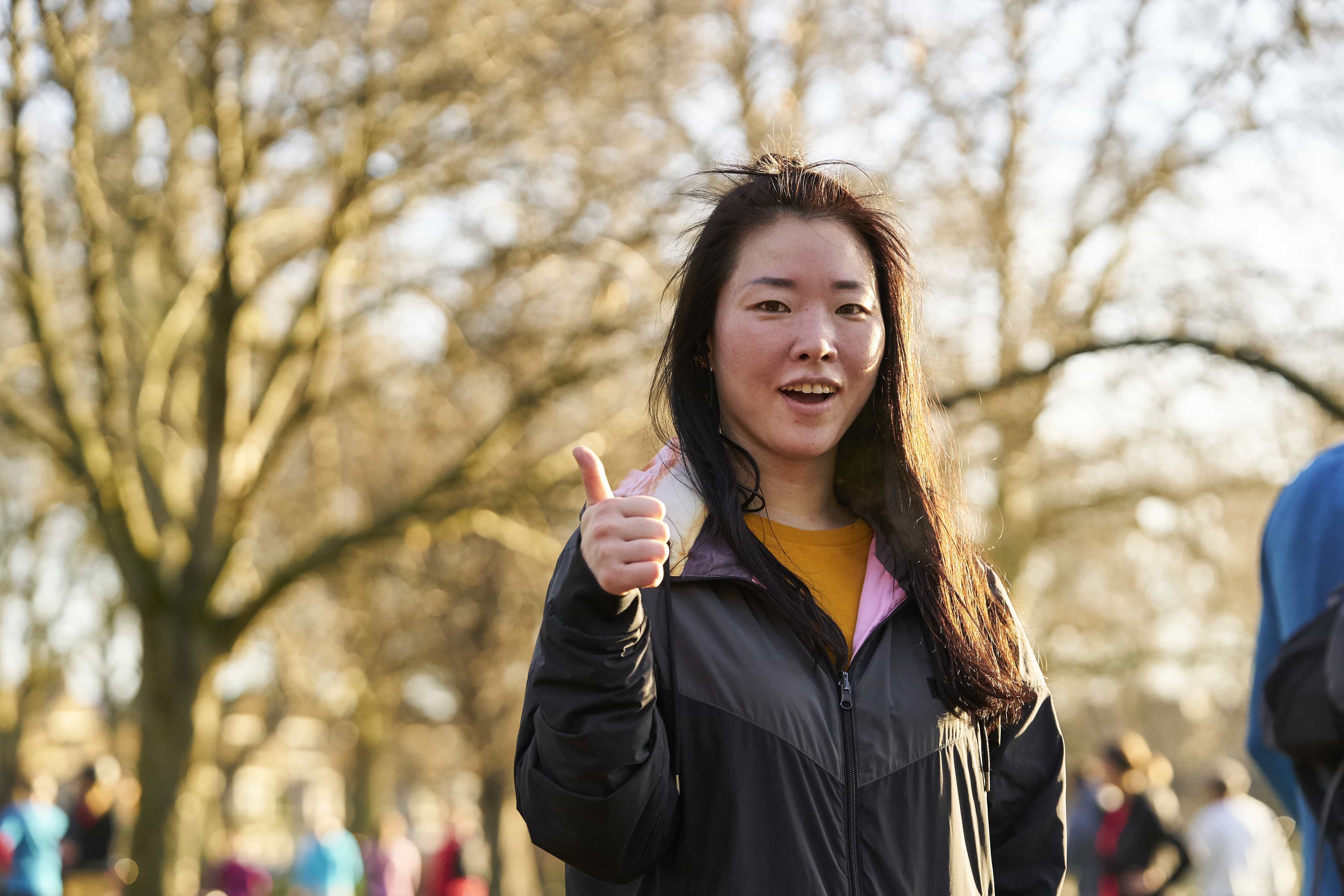 young female volunteer in a park giving a thumbs up