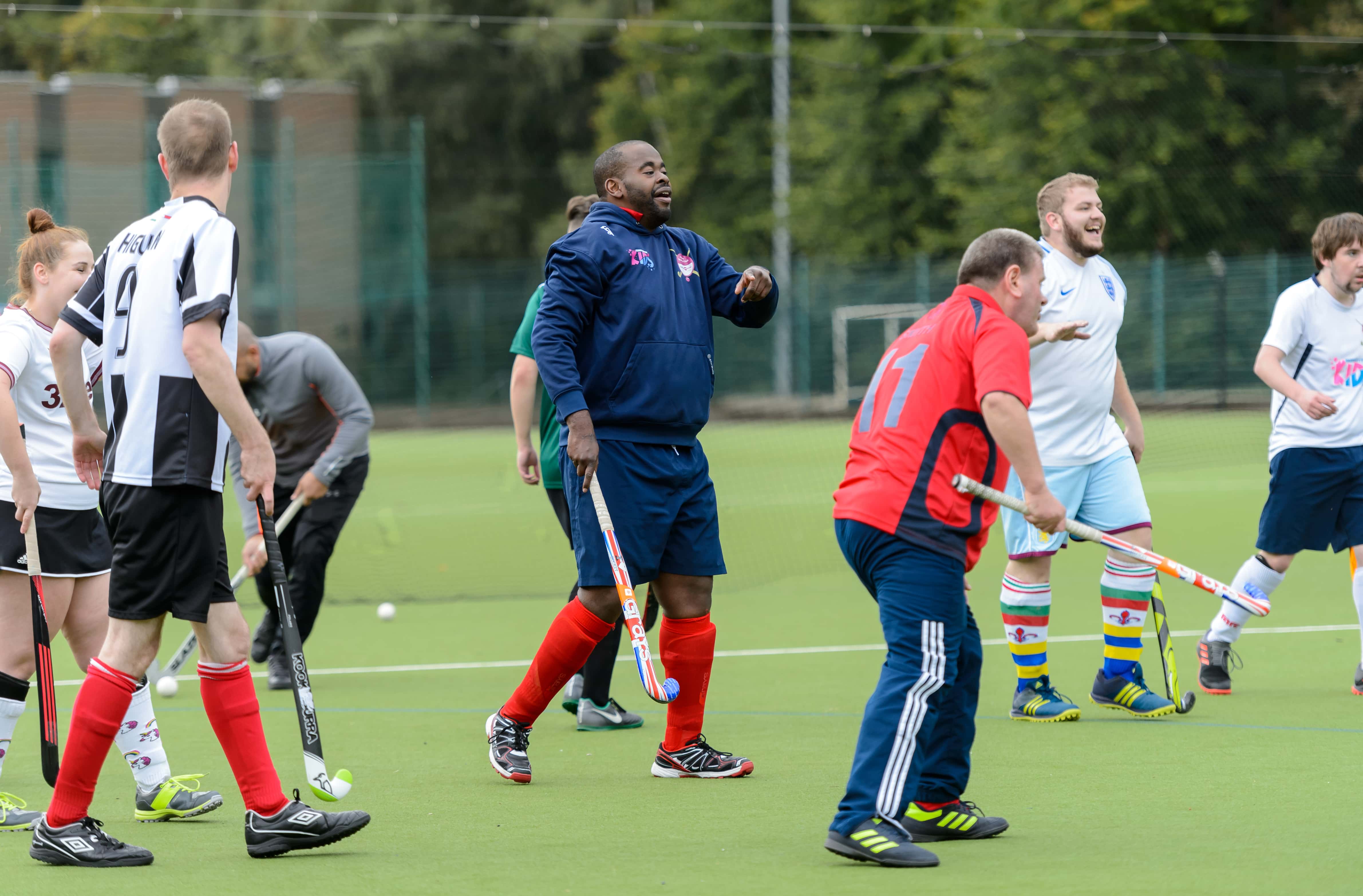 group of  adults on an astro turf taking part in a hockey session