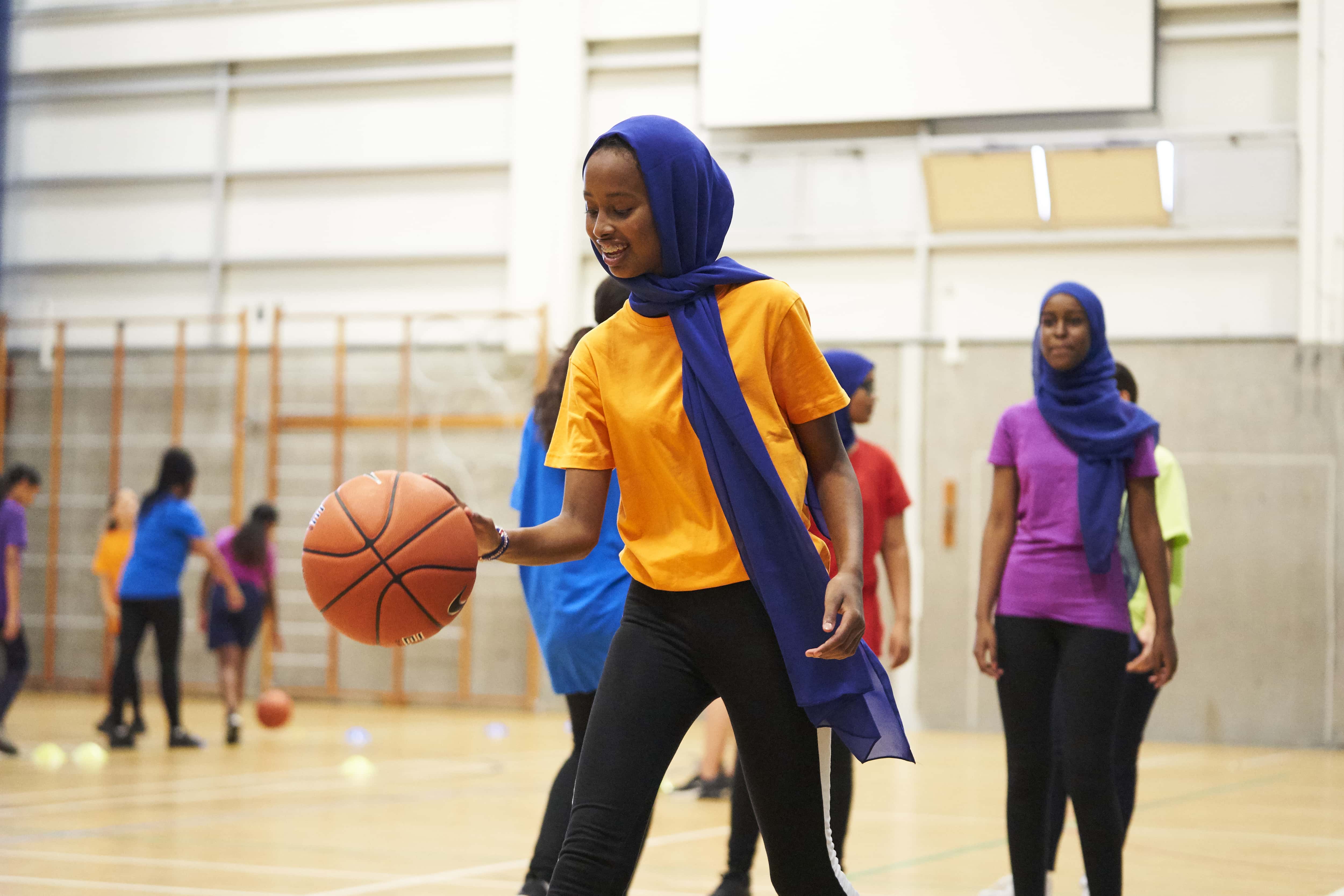 Girl wearing head scarf dribbling basketball