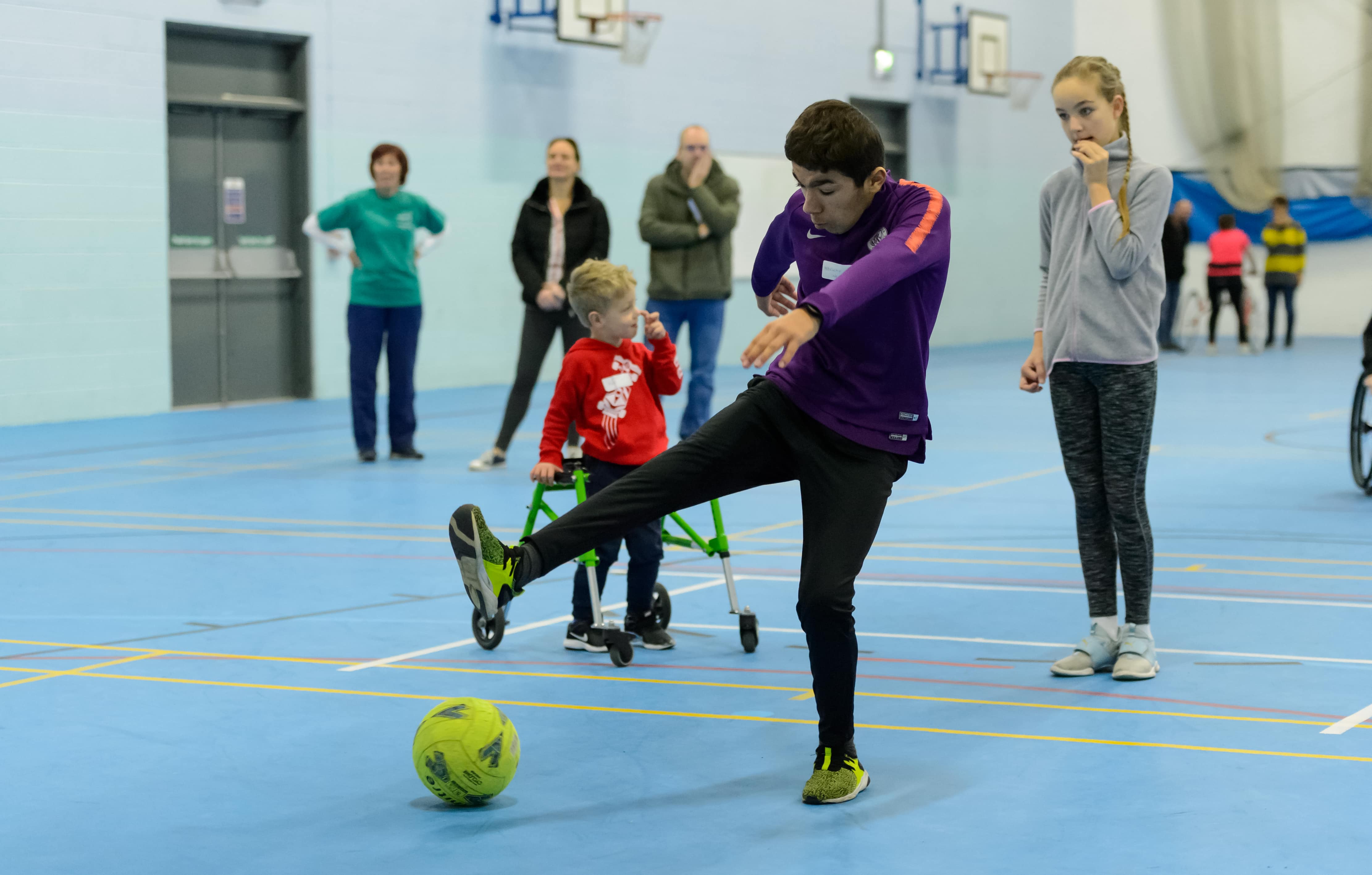 mixed group of young people with disabilities playing football in sportshall 