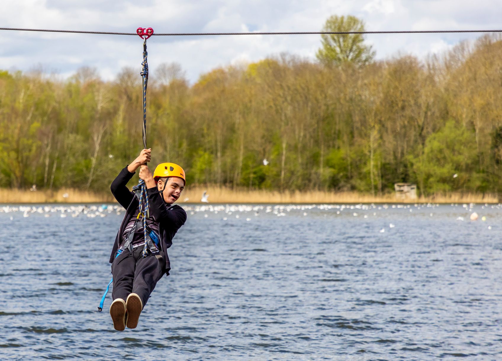 child travelling on a zip-line over a lake
