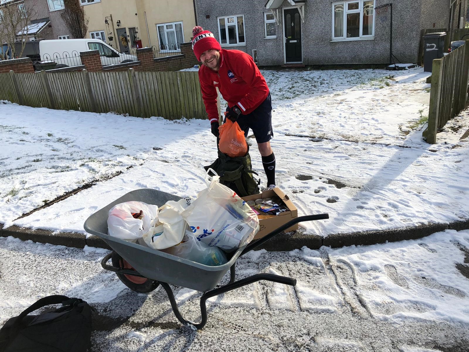 Geoff collecting food parcels in a wheelbarrow in the snow