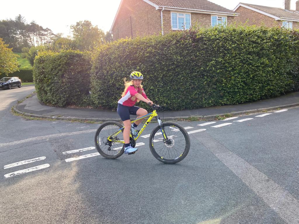 A female young carer enjoying riding her mountain bike by her house 