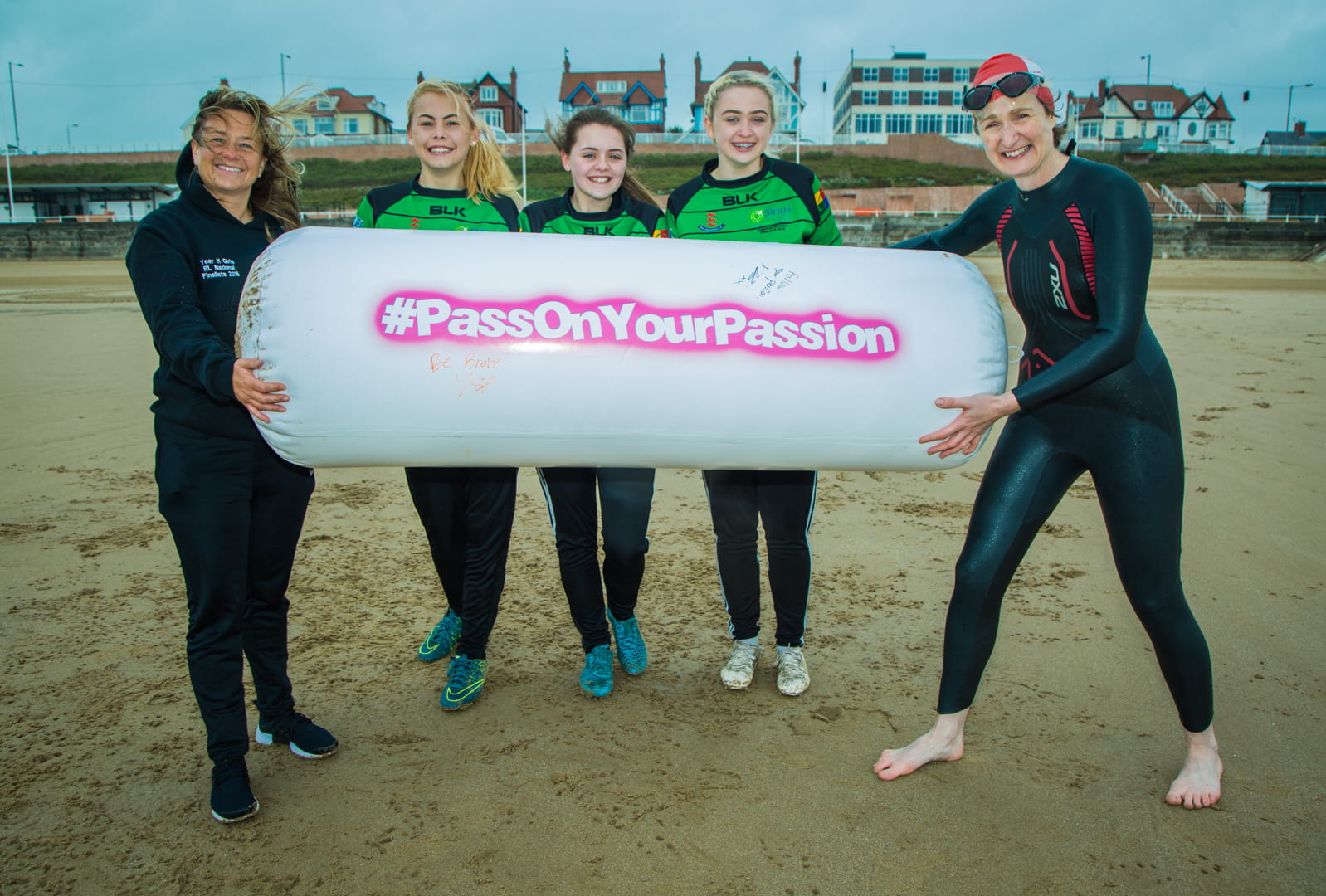 Female coaches on beach passing on inflatable batton