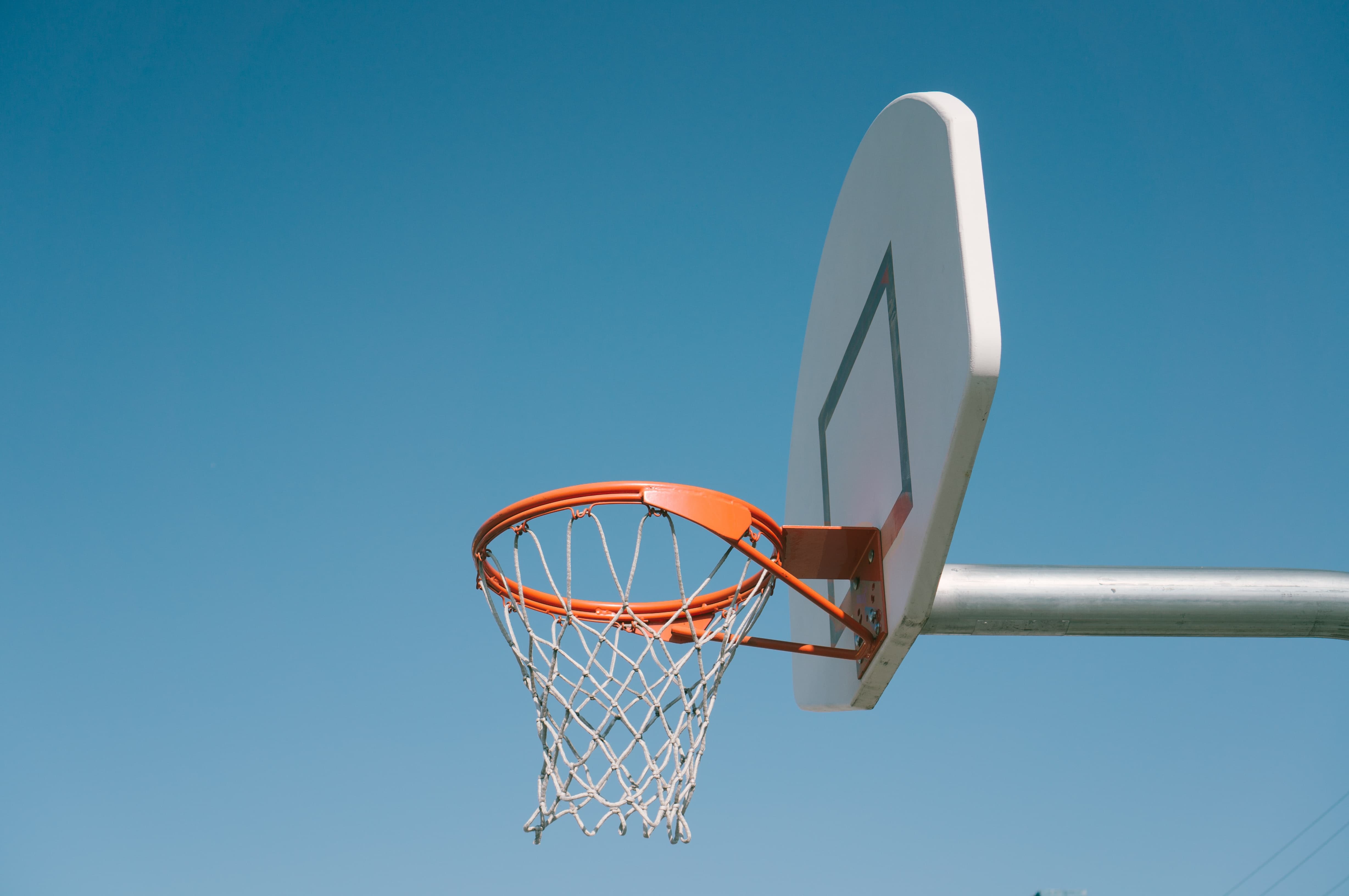 single basketball hoop and backboard against a blue sky 