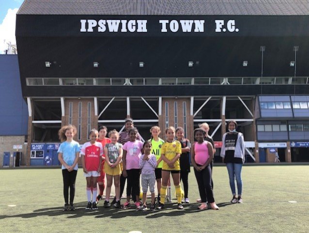 Group of girls in shorts and t-shirts standing on the Ipswich football pitch 