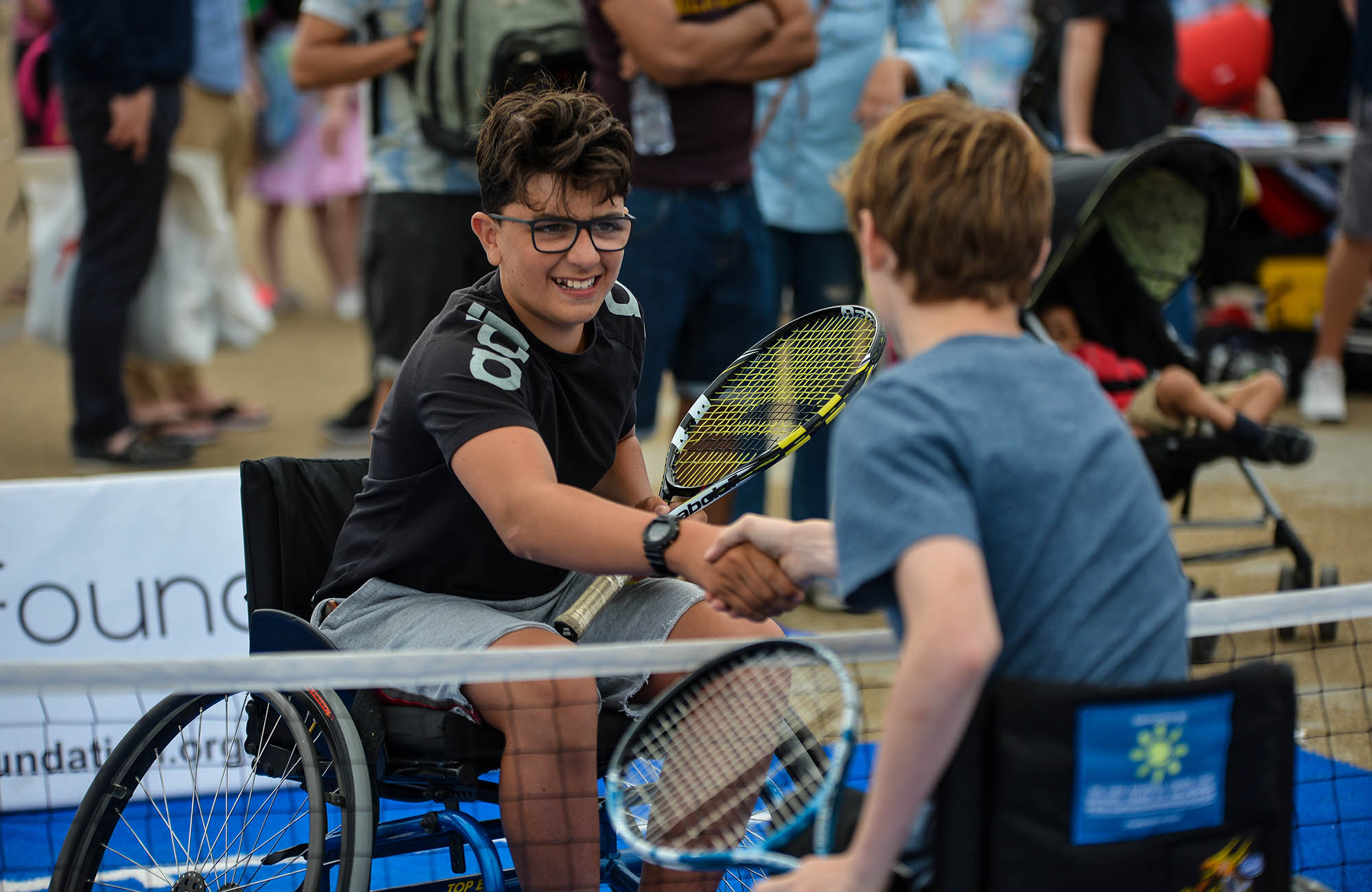 Two wheelchair players shaking hands over the net
