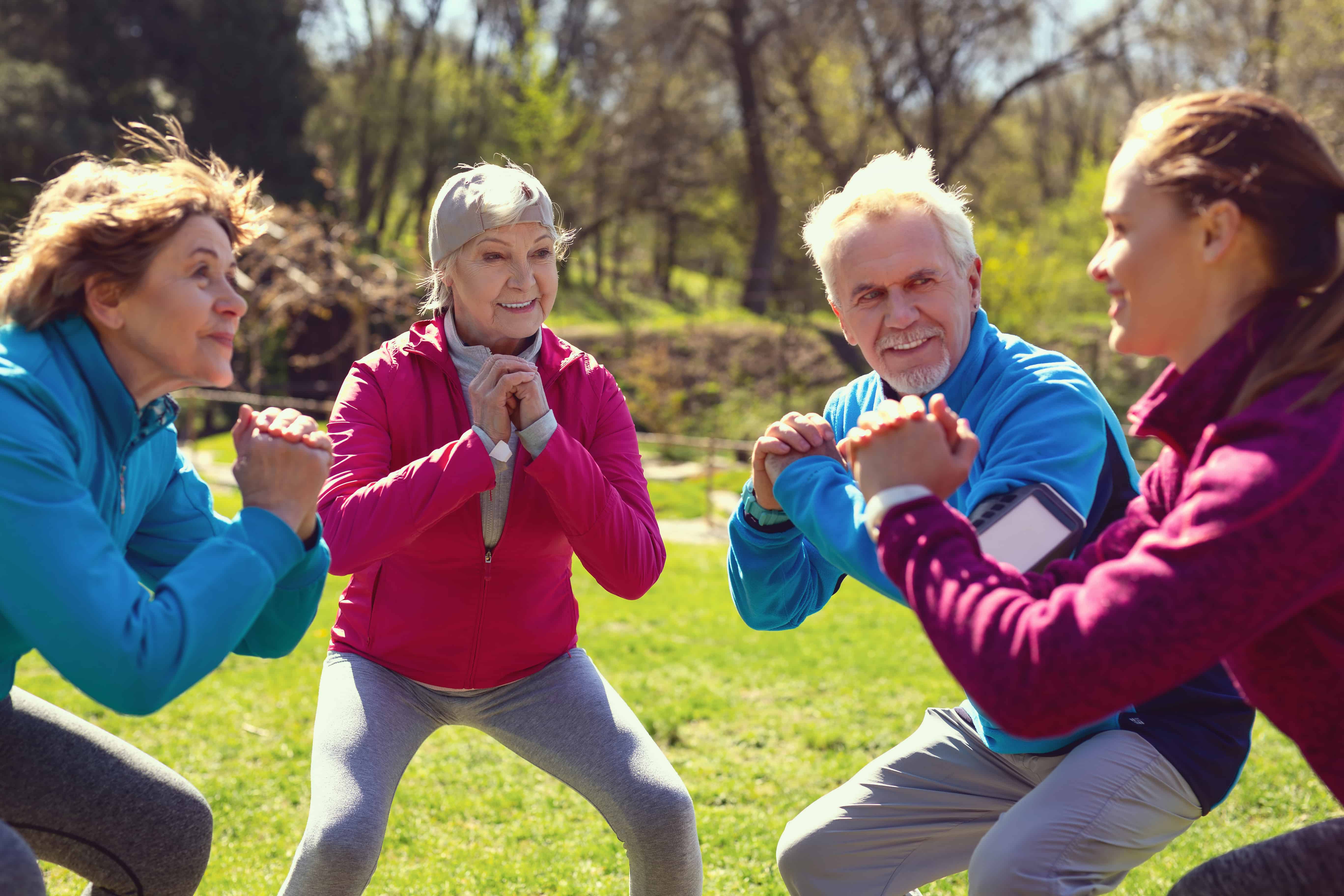 4 older people in chatting in a circle whilst in a squat position 