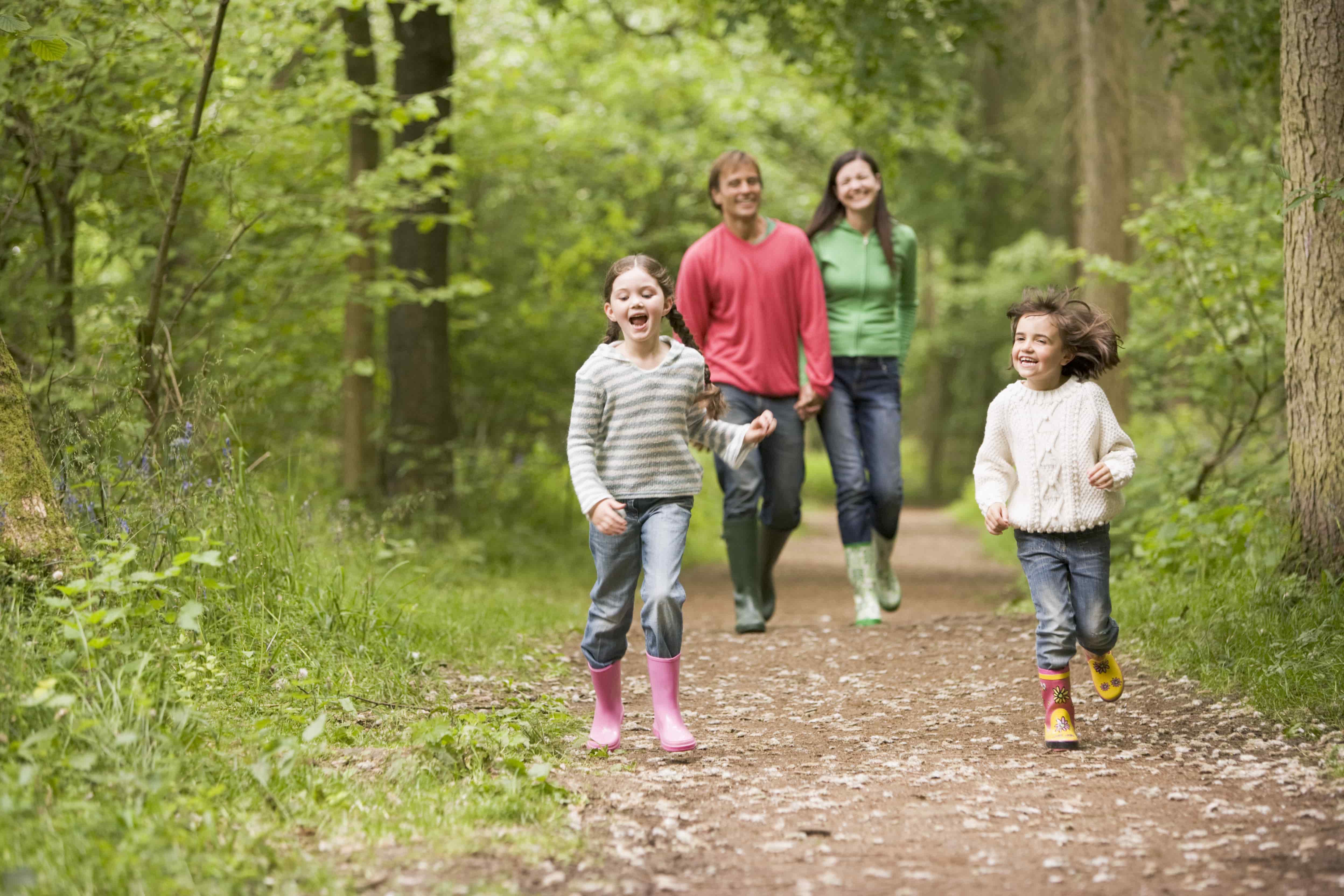 A family with two daughters wearing wellies running in the park