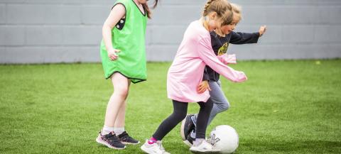 Three young girls playing football 