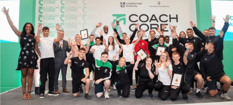 group of apprenticeships cheering against a backdrop branded coach core