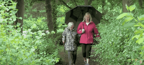 96 year old Majorie enjoying a walk in woods with another female working.
