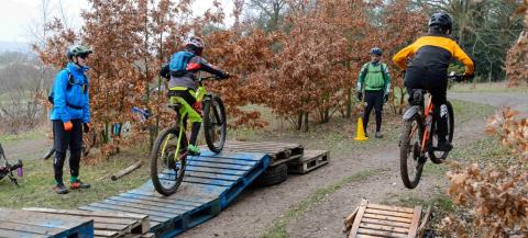 two people on mountain bikes being coaches to go over a ramp