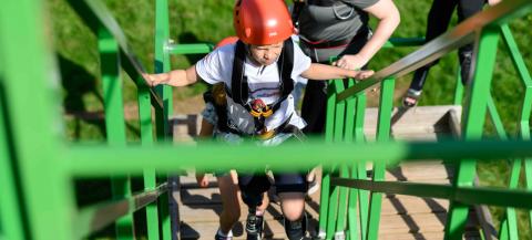 disabled young boy walking up a ladder on an obstacle course