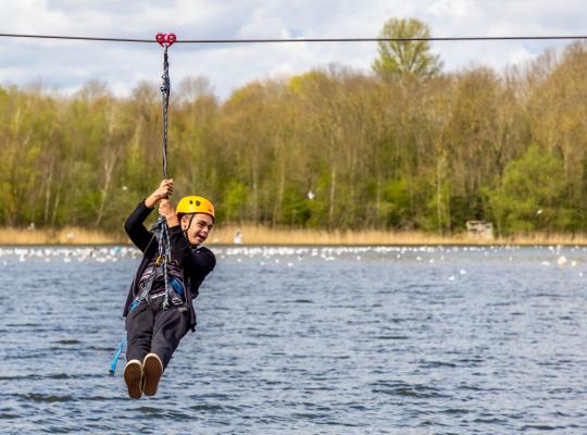child travelling on a zip-line over a lake