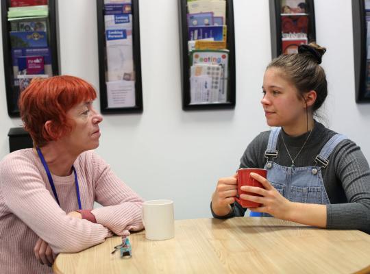 two women talking around a desk 