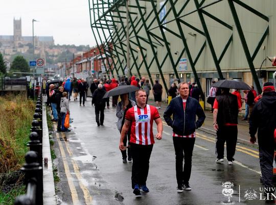 supporters walking by a football stadium 