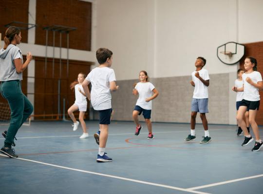 group of children playing badminton in a sports hall